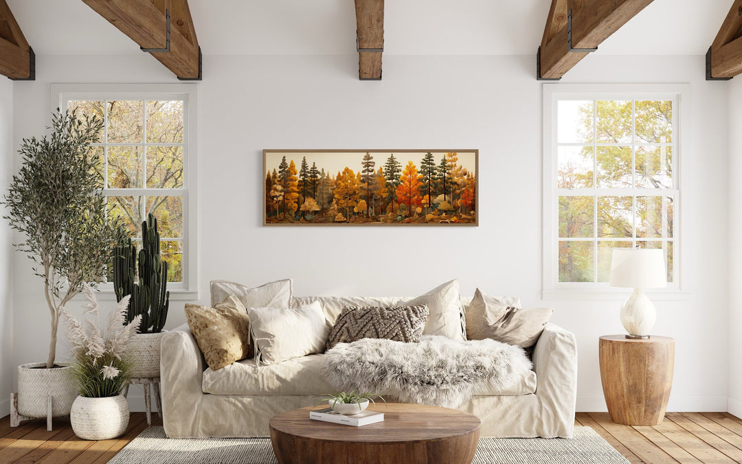 Long horizontal autumn forest painting on wood above a sofa in a rustic living room.