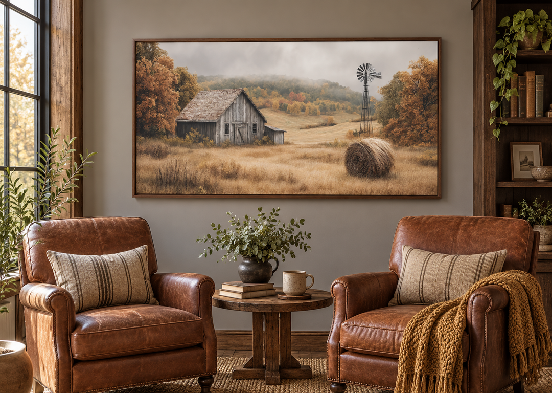 Rustic barn, hay bale, and windmill canvas wall art in a fall landscape above leather armchairs.
