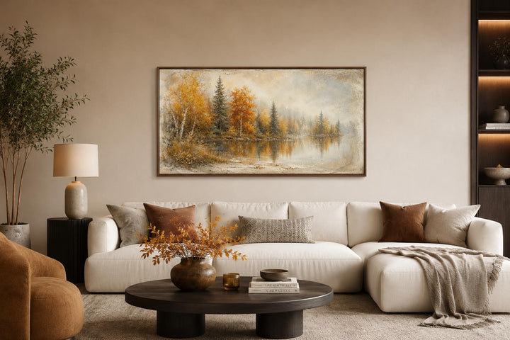 Autumn Lake Wall Art featuring a misty lake and fall forest in a rustic frame above a white sofa.