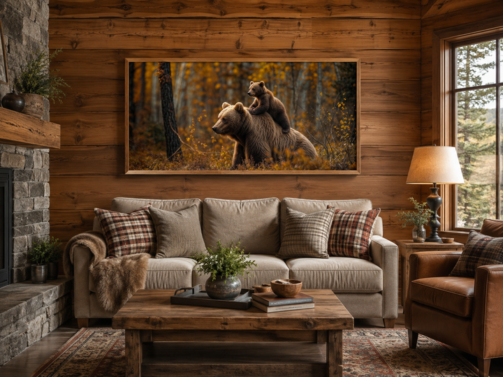 Framed canvas art of a baby bear riding a mama bear in an autumn forest above a living room sofa.