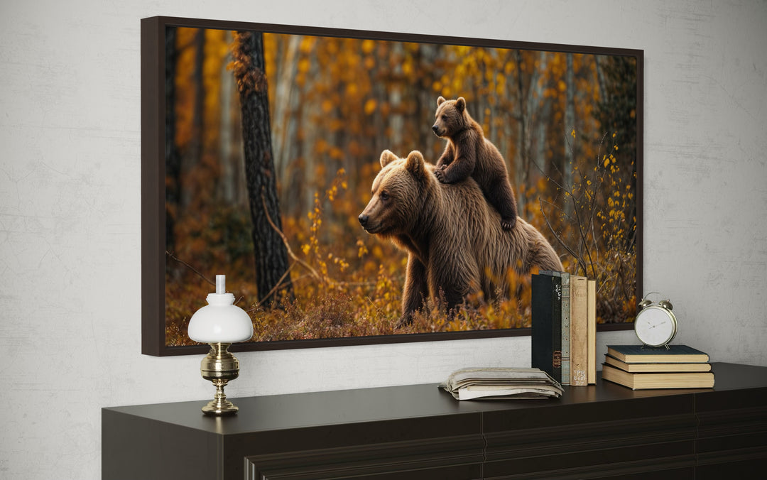 Framed canvas wall art of a baby bear riding on its mother's back in an autumn forest.