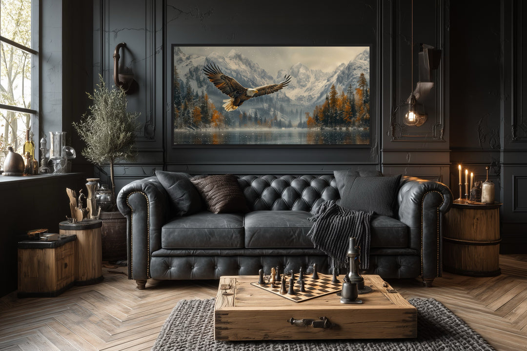 Framed wall art of a bald eagle flying over a snowy mountain lake in a dark, rustic living room.