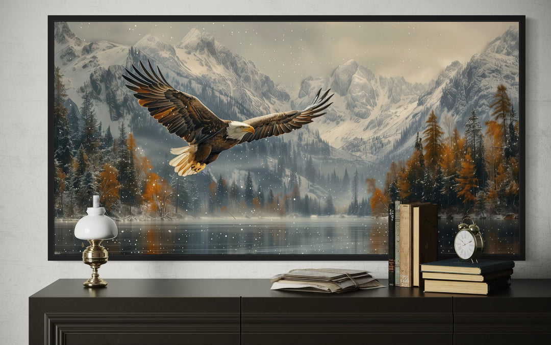 Framed wall art of a bald eagle flying over a snowy mountain lake in a rustic office setting.