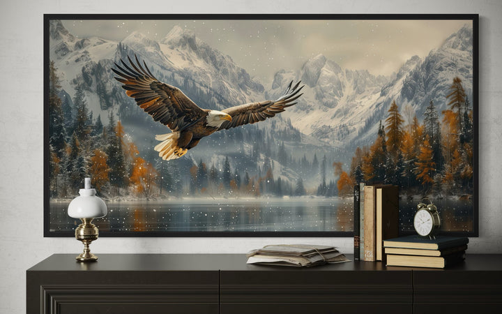 Framed wall art of a bald eagle flying over a snowy mountain lake in a rustic office setting.