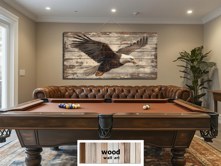 A rustic wood wall art piece featuring a bald eagle in flight hangs above a pool table and sofa.