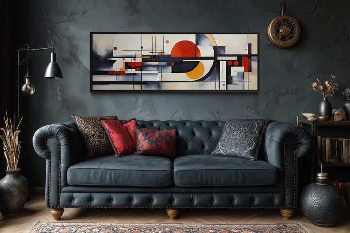 Bauhaus abstract geometric canvas print in a panoramic frame above a dark blue tufted sofa.