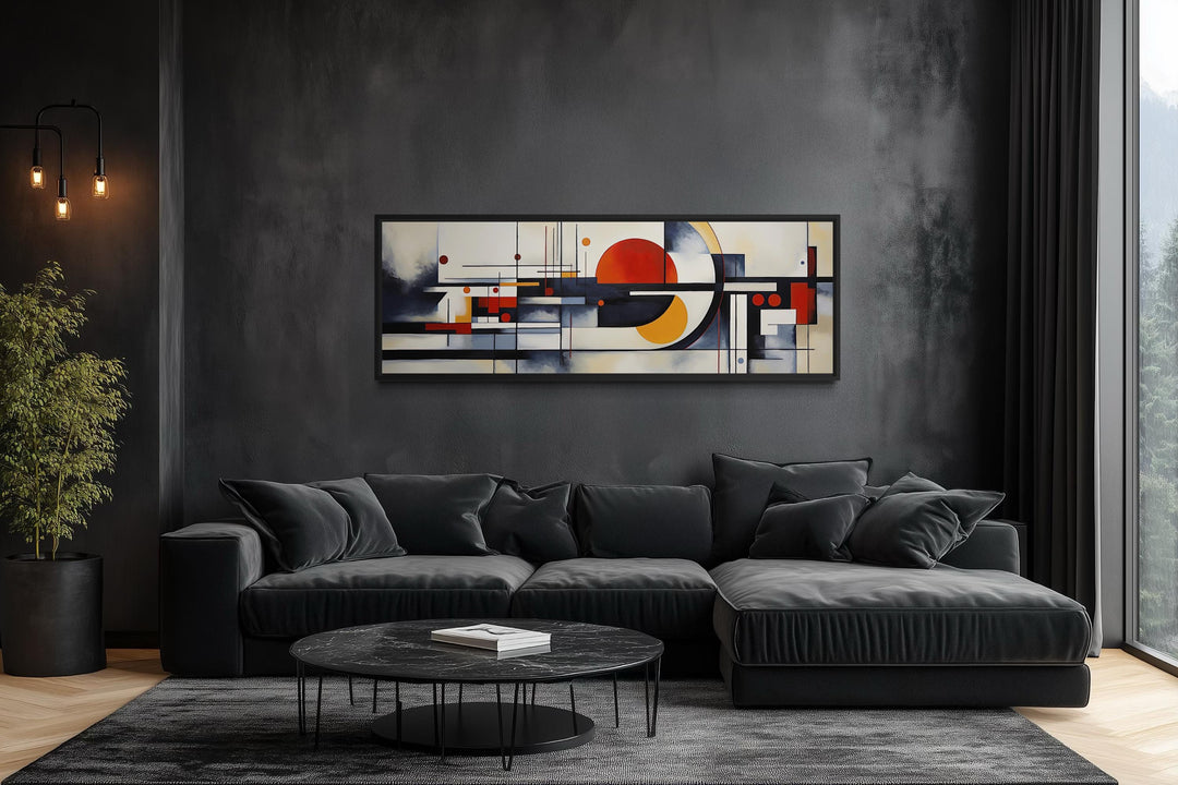 Bauhaus abstract geometric canvas print in a panoramic frame above a modern black sectional sofa.