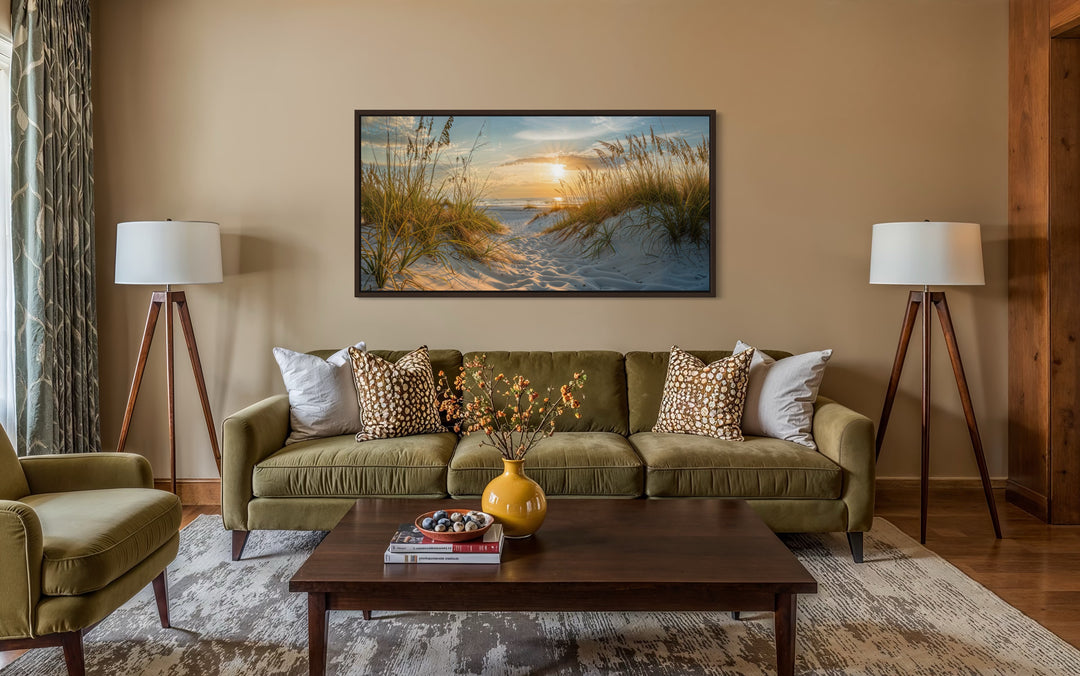 Framed beach sunset wall art featuring sand dunes and ocean over a green sofa in a living room.