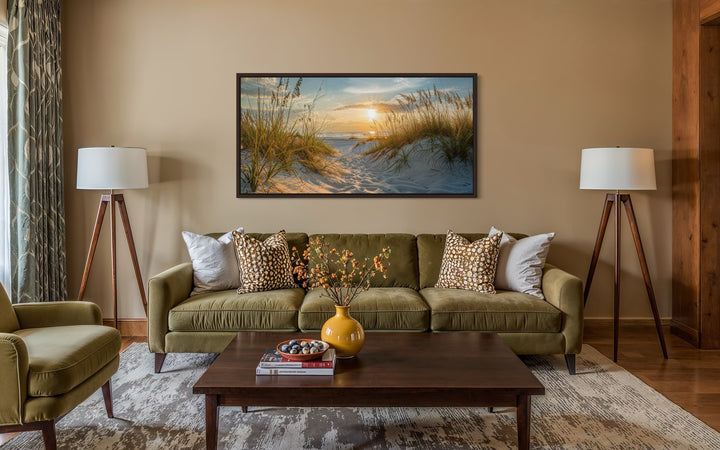 Framed beach sunset wall art featuring sand dunes and ocean over a green sofa in a living room.