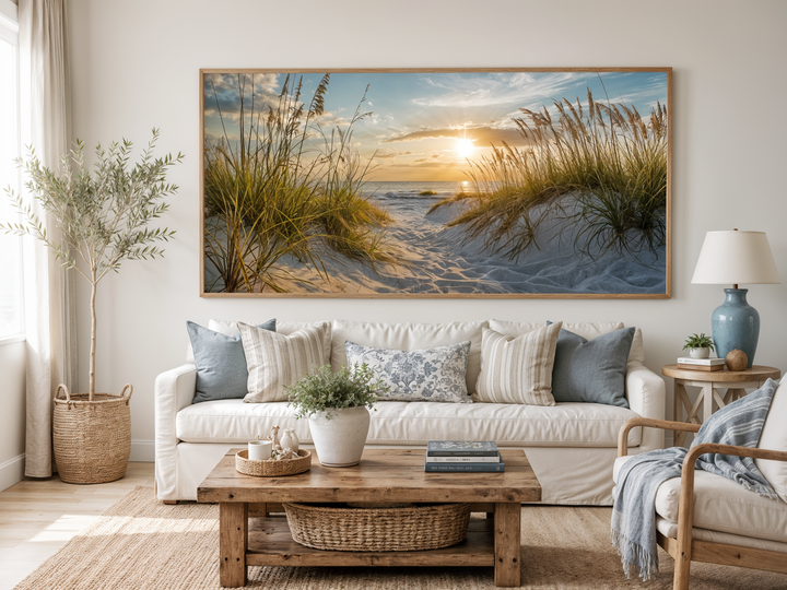 Framed beach sunset wall art featuring sand dunes and coastal grass above a white sofa.