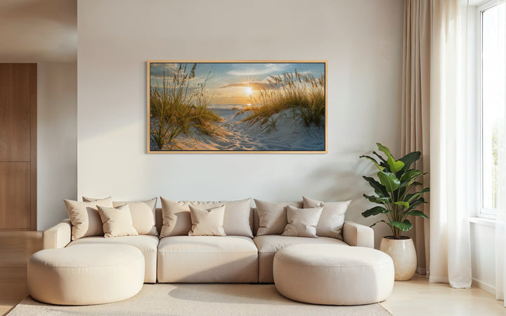 Framed beach sunset wall art featuring sand dunes and ocean waves above a beige sectional sofa.