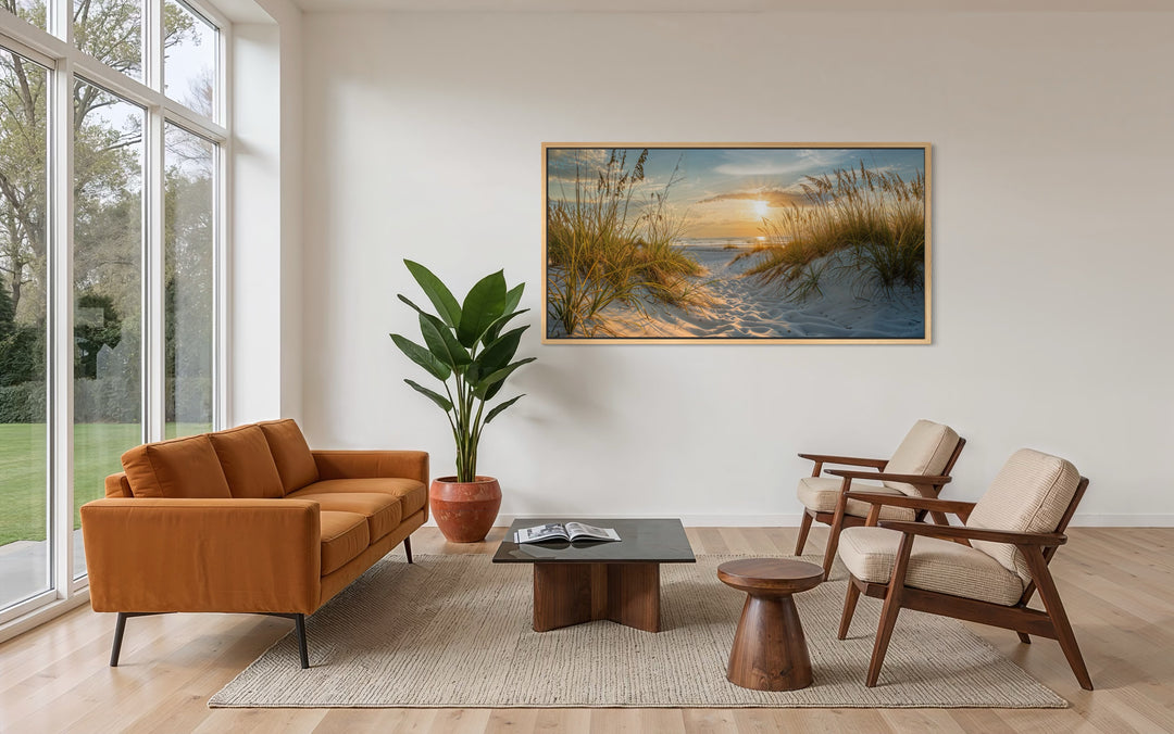 Framed beach sunset wall art featuring sand dunes and ocean waves in a modern living room.