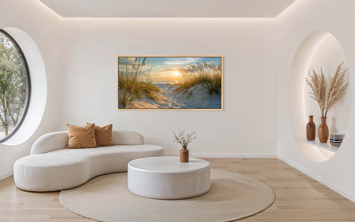 Framed beach sunset wall art featuring sand dunes and ocean waves in a modern living room.