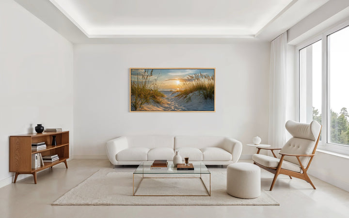 Framed beach sunset wall art featuring sand dunes and ocean over a white sofa in a modern room.