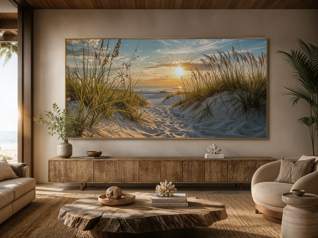 Large framed canvas art of a beach sunset with sand dunes and grass above a wooden console table.