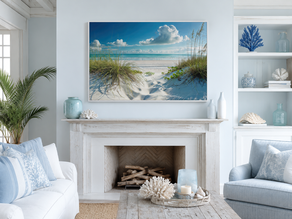 Coastal framed canvas wall art of sand dunes and grass on a beach above a white fireplace.