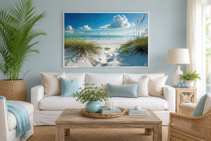 Framed coastal canvas wall art of sand dunes and grass on a beach above a white sofa.