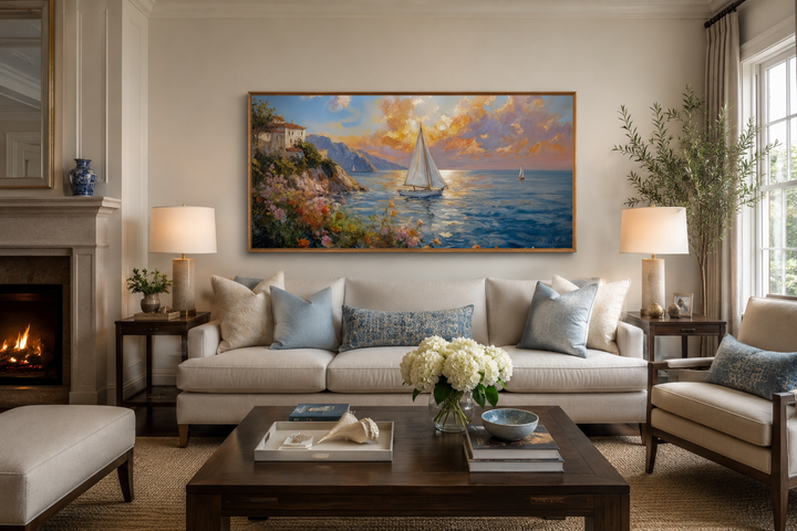 Modern coastal framed canvas print of a sunset seascape with sailboats above a living room sofa.