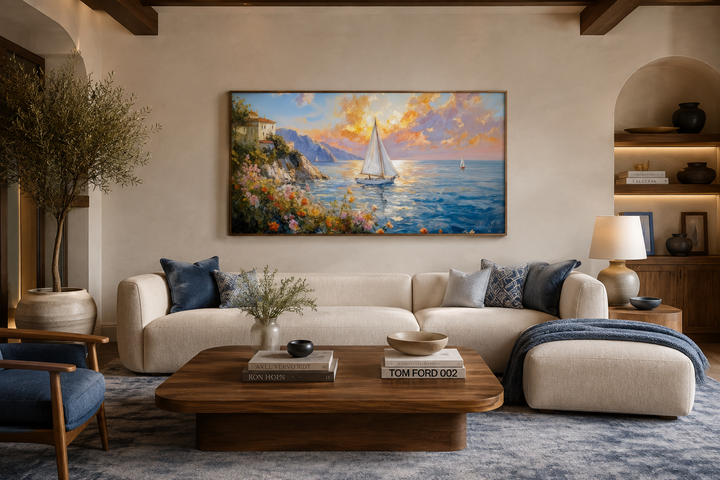 Modern coastal framed canvas print of a sunset seascape with sailboats above a cream sofa.
