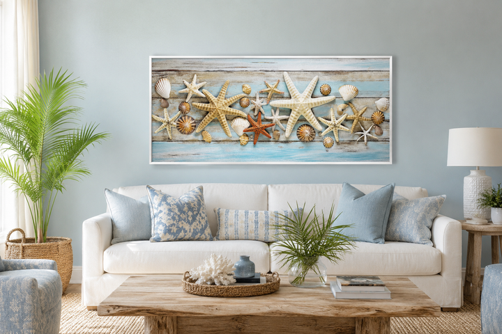 Framed horizontal starfish and seashells wall art above a white sofa in a coastal living room.