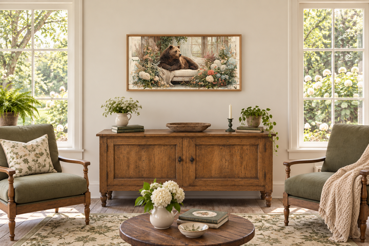Bear on Couch Floral Canvas Wall Art in a wood frame above a rustic sideboard in a sunlit room.