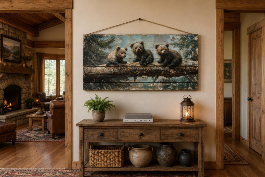 Rustic wood panel print of three bear cubs on a log, hanging above a wooden console table.