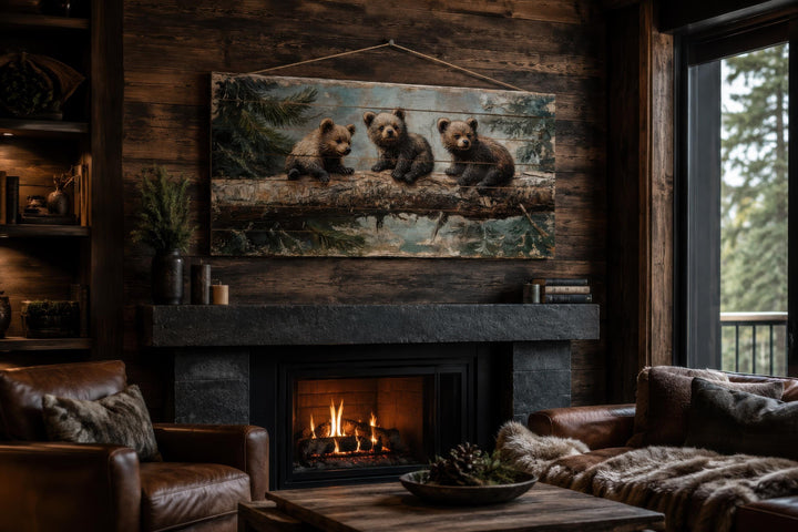 Rustic wood panel print of three bear cubs on a log, hanging above a fireplace in a cozy cabin.