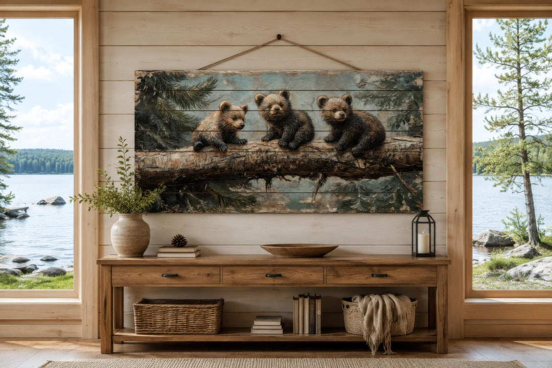 Rustic wood panel print of three bear cubs on a log, hanging above a console table in a cabin.