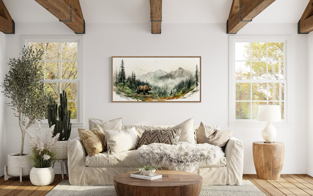 Bear in the forest mountain landscape wall art in a rustic living room with a white sofa.