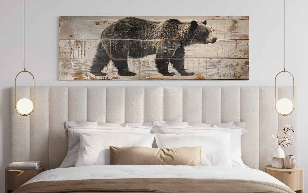 Bear painted on wood long horizontal framed canvas wall art hanging above a bed in a cabin.