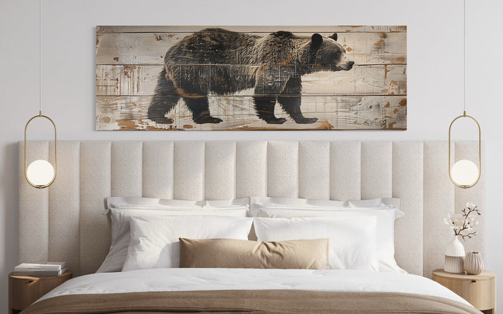 Bear painted on wood long horizontal framed canvas wall art hanging above a bed in a cabin.