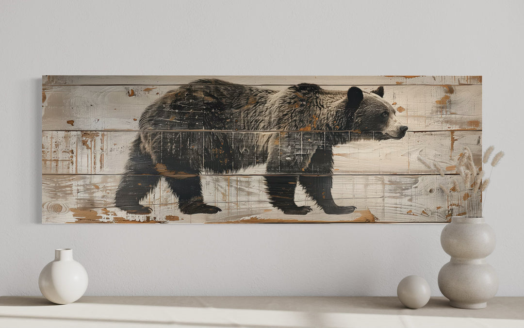 Long horizontal canvas wall art of a bear painted on rustic wood planks for cabin decor.