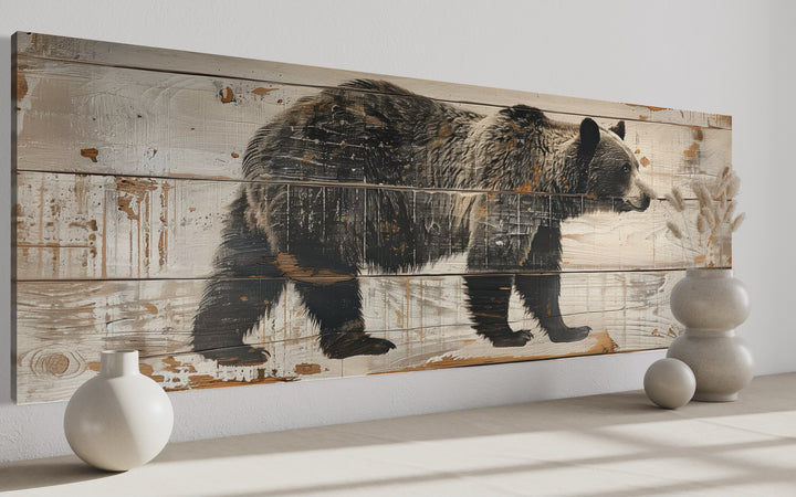 Long horizontal framed canvas wall art of a bear painted on rustic wood planks for cabin decor.