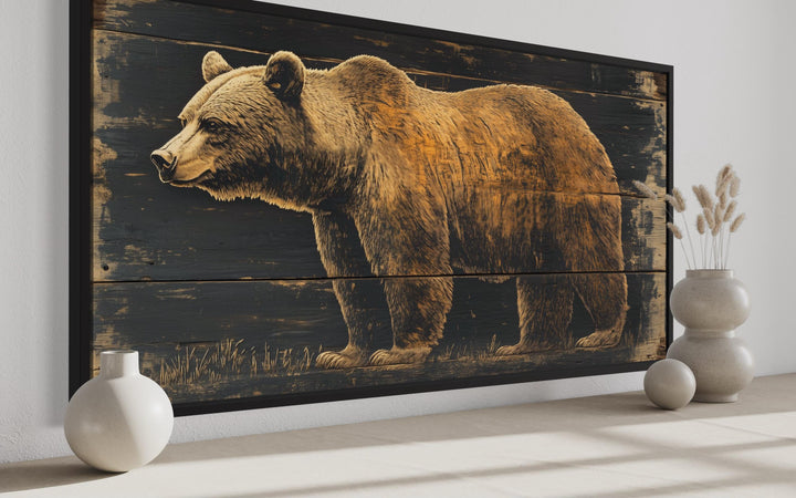 Bear painted on dark wood framed canvas wall art displayed in a rustic cabin setting.