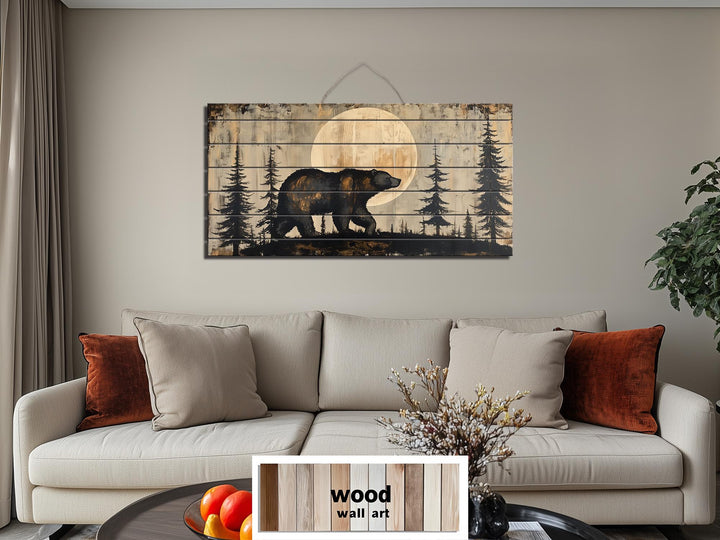 Rustic wood wall art featuring a bear walking through a forest under a full moon above a sofa.
