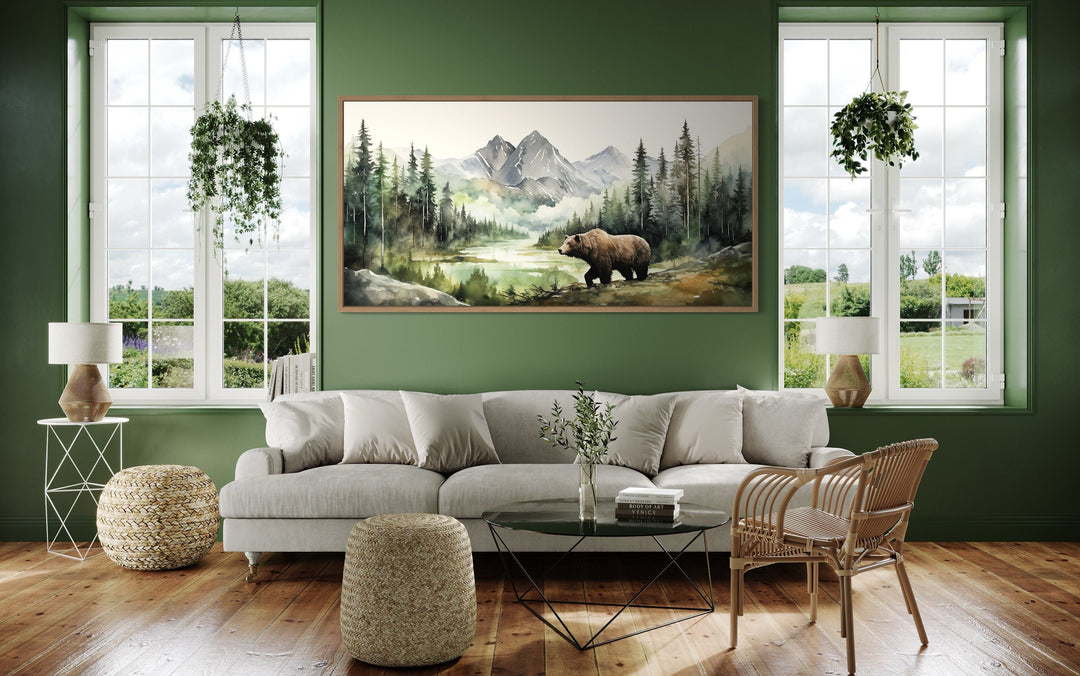 Large watercolor canvas of a bear in a mountain forest hanging in a green rustic living room.