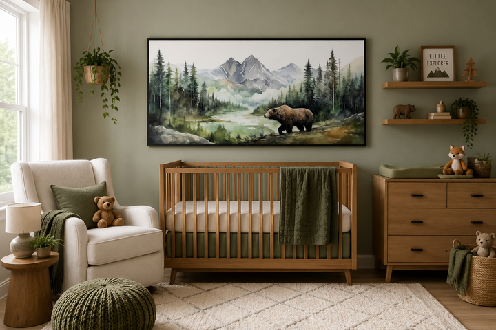 Large framed watercolor painting of a bear in a mountain forest hanging above a wooden baby crib.