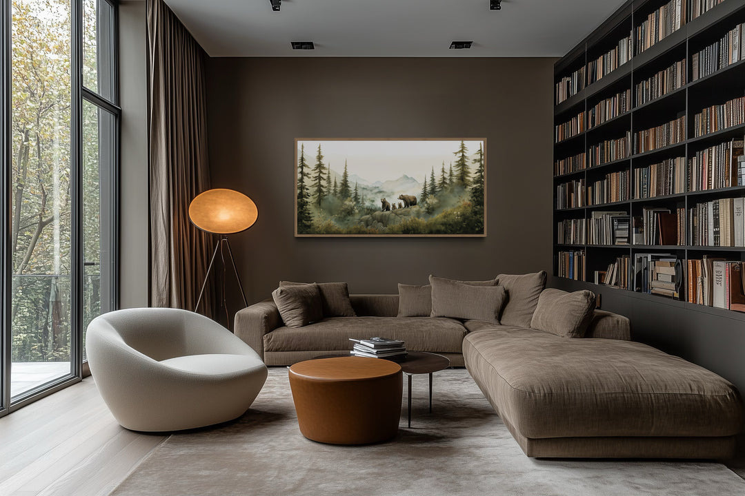 Framed watercolor wall art of a bear family in a forest above a brown sectional sofa in a modern den.