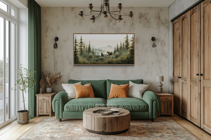 Bears family with cubs in a forest watercolor painting in a wood frame above a green sofa.