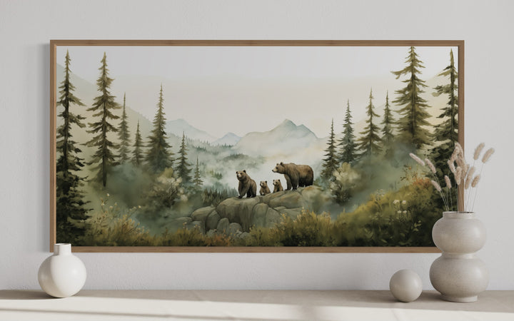 Framed watercolor painting of a bear family with cubs on a rocky outcrop in a misty pine forest.