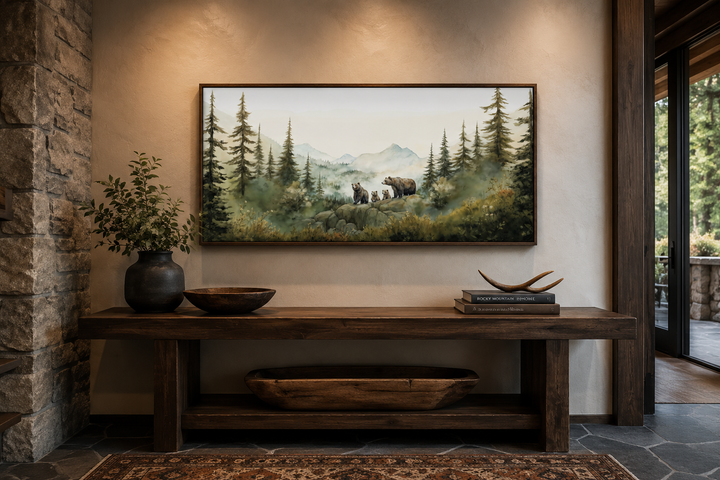 Framed watercolor wall art of a bear family with cubs in a misty forest above a wooden console.