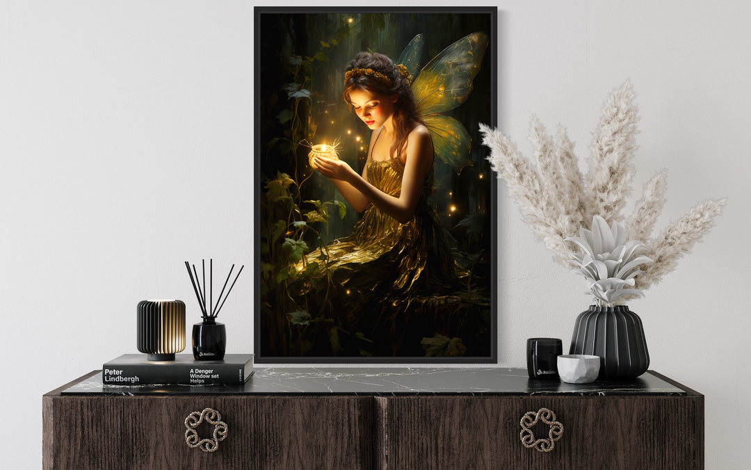Framed canvas wall art of a forest fairy holding a glowing firefly above a dark wood dresser.
