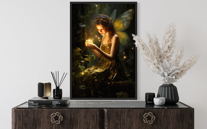 Framed canvas wall art of a forest fairy holding a glowing firefly above a dark wood dresser.