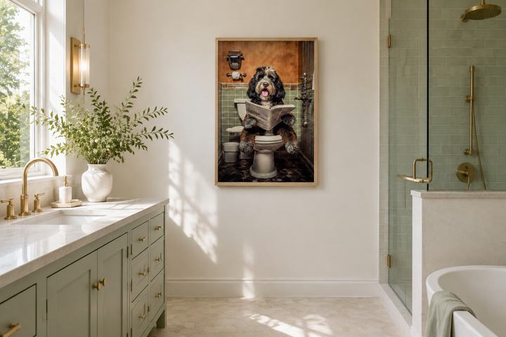 Framed canvas wall art of a Bernedoodle dog sitting on a toilet reading a newspaper in a bathroom.