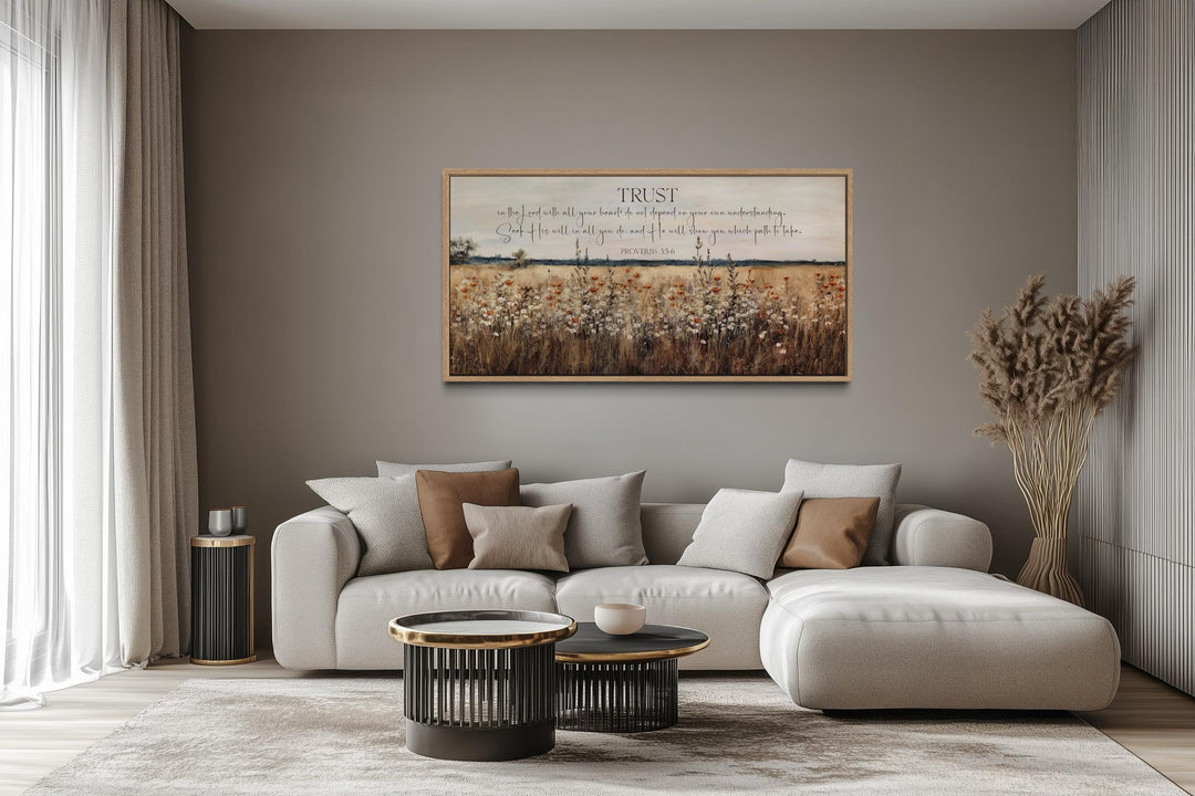 Bible Verse wall art featuring Proverbs 3:5 over a golden wildflower field in a modern living room.