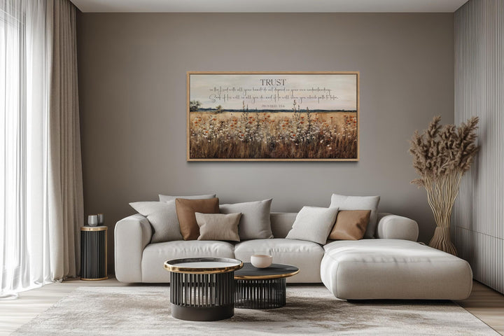 Bible Verse wall art featuring Proverbs 3:5 over a golden wildflower field in a modern living room.
