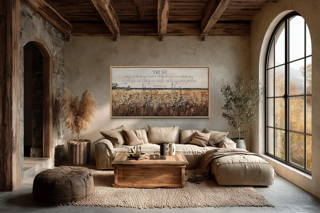 Horizontal Proverbs 3:5 scripture canvas with a wildflower field above a sofa in a rustic room.