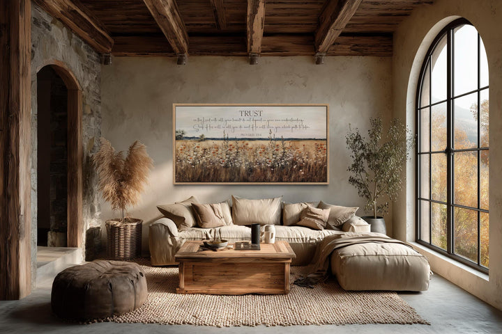 Horizontal Proverbs 3:5 scripture canvas with a wildflower field above a sofa in a rustic room.
