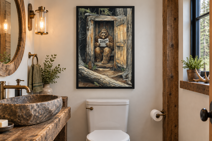Bigfoot reading a newspaper in a wooden outhouse canvas wall art in a rustic cabin bathroom.