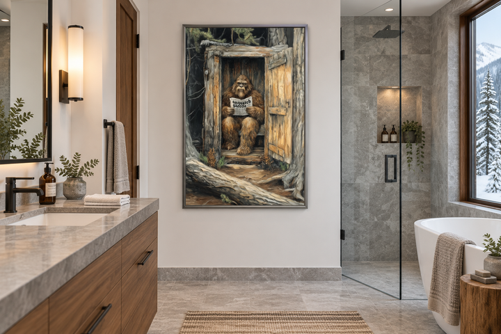 Bigfoot in an outhouse reading a newspaper canvas wall art in a modern cabin bathroom.